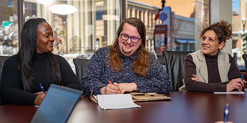 Three 网赌网站 employees at a conference table in the Dubuque Center.