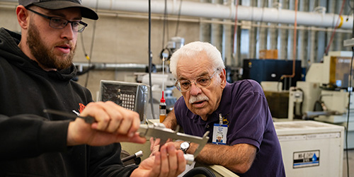 A CNC student works with an instructor.