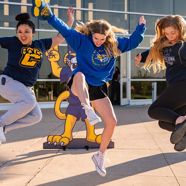 Three 网赌网站 students jump for a photograph in front of the Peosta entrance.