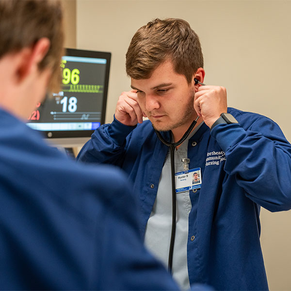 An 网赌网站 nursing student adjusts his stethoscope while in the nursing simulation lab.