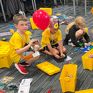 Young campers building with LEGO bricks on the ground