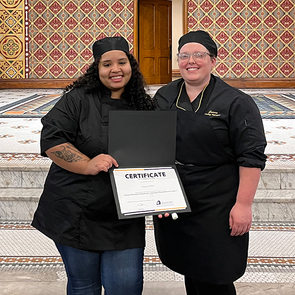 阿莱米勒 holding her Culinary Foundations certificate, pictured next to an 网赌网站 instructor.