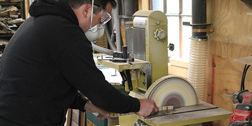 A male carpentry student works at a table saw.