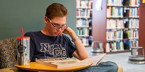Male student studies in the library