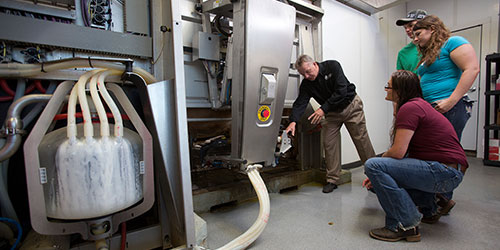 网赌网站 students listen to an instructor explain a machine at the dairy facility.